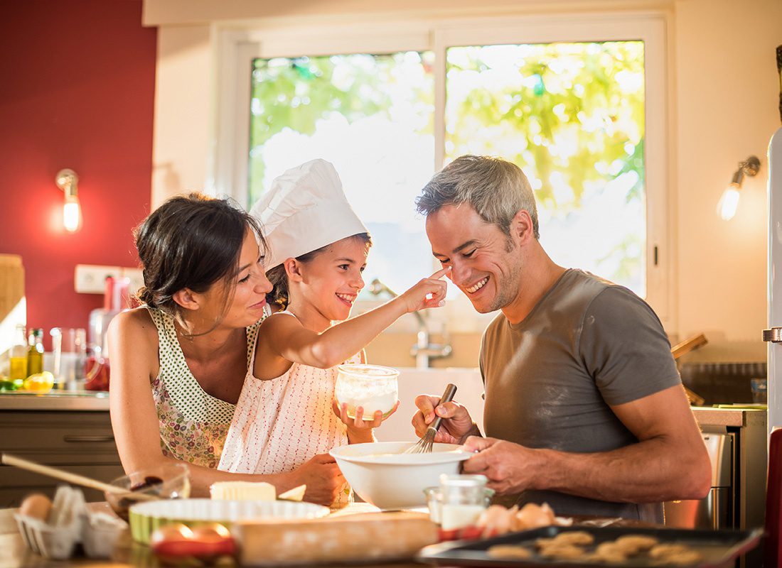 Read Our Reviews - Portrait of a Young Daughter Wearing a Chef Hat Having Fun Cooking With her Parents in the Kitchen at Home