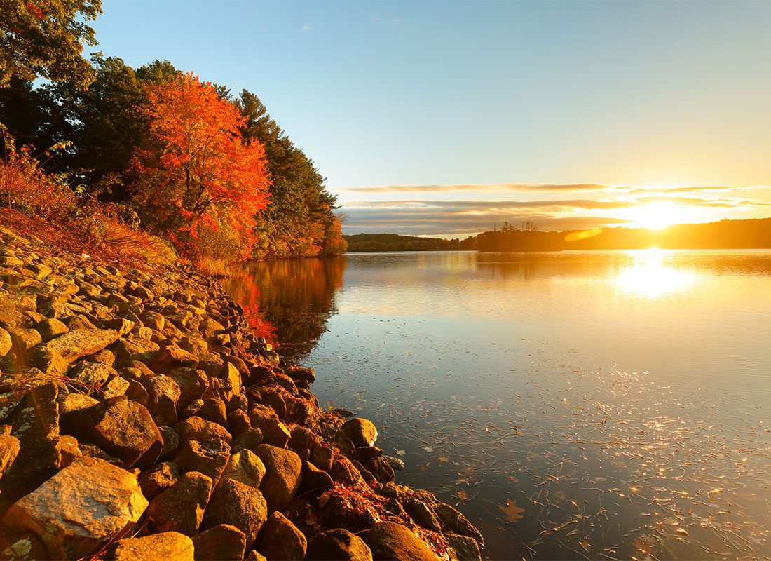 Southborough, MA - Scenic View of the Sunset Over a Lake Surrounded by Colorful Fall Foliage in Southborough Massachusetts