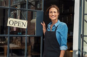 woman standing outside business with open sign on door